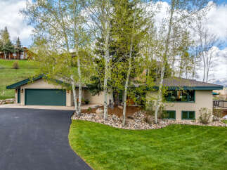 This stunning property boasts a beautiful exterior with a lush green lawn and mature trees.