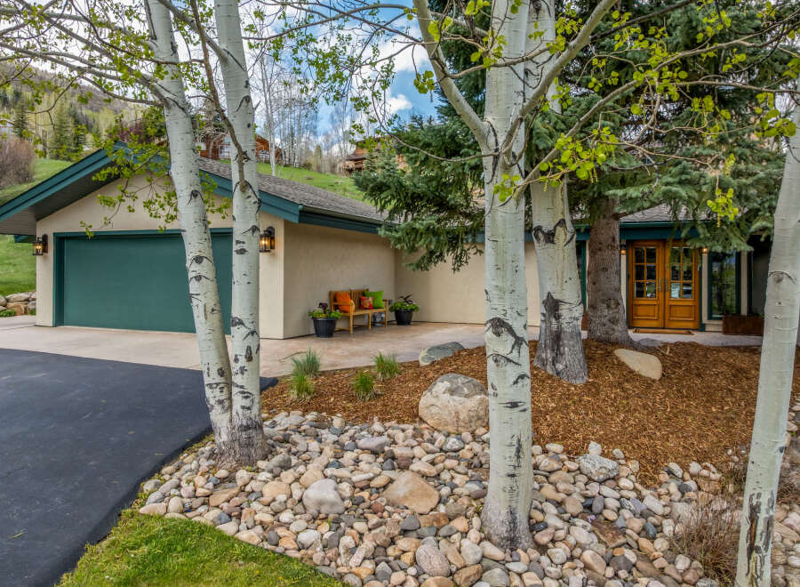 This stunning property boasts a beautiful exterior with mature trees and lush landscaping, creating a serene and inviting atmosphere.