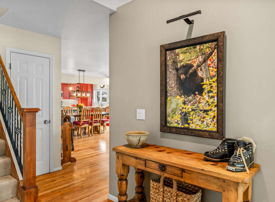 This inviting entryway showcases a rustic wooden console table adorned with a decorative bowl and stylish boots, creating a warm and welcoming atmosphere.