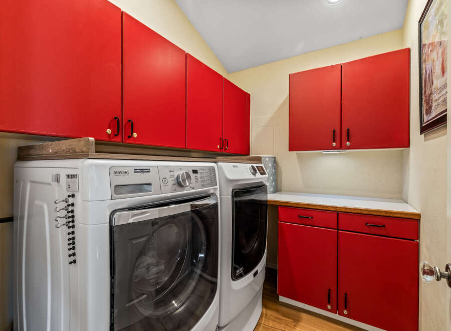 This laundry room features a modern design with vibrant red cabinetry, offering ample storage space.