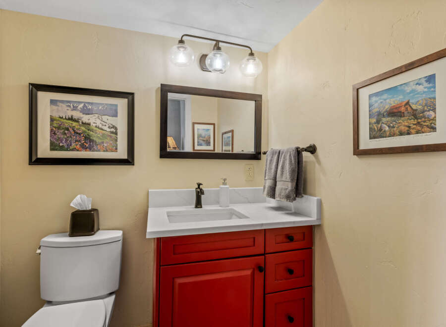 This charming bathroom features a vibrant red vanity, offering a pop of color against the neutral walls.