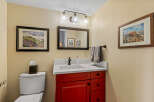 This charming bathroom features a vibrant red vanity, offering a pop of color against the neutral walls.