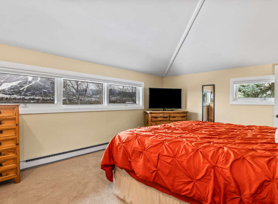 This cozy bedroom features a stunning mountain view through large windows, creating a serene atmosphere.