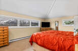 This cozy bedroom features a stunning mountain view through large windows, creating a serene atmosphere.