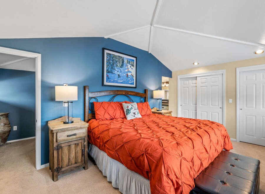 This inviting bedroom features a cozy bed with a vibrant orange comforter, creating a warm and inviting atmosphere.