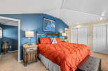 This inviting bedroom features a cozy bed with a vibrant orange comforter, creating a warm and inviting atmosphere.