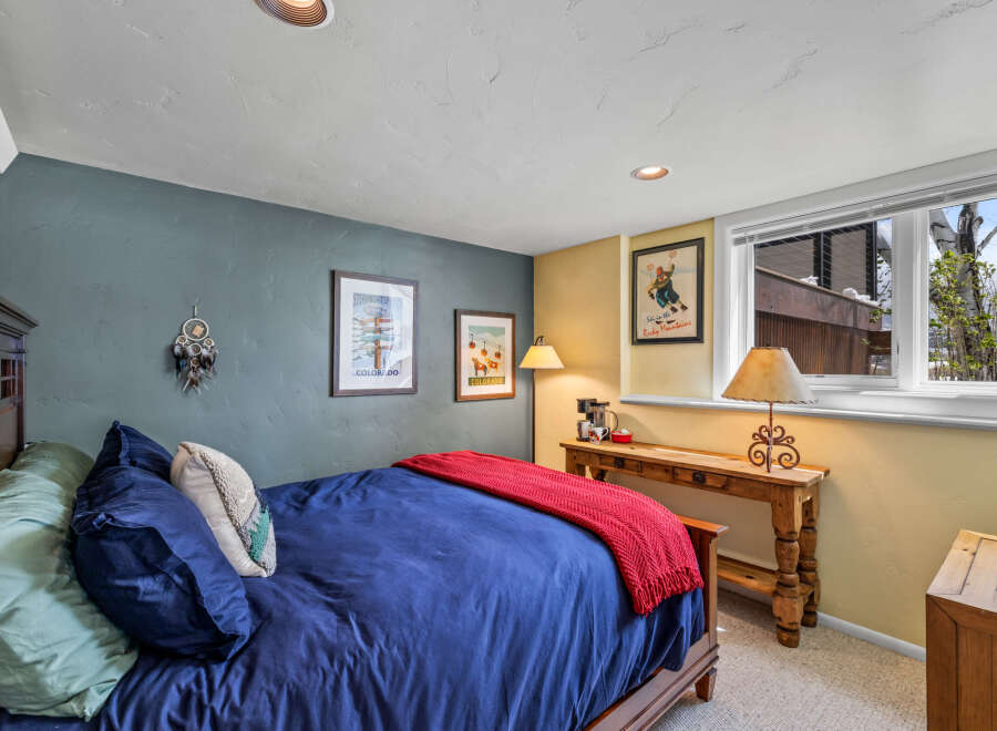 This cozy bedroom features a comfortable bed with a vibrant blue comforter and a warm red throw blanket.