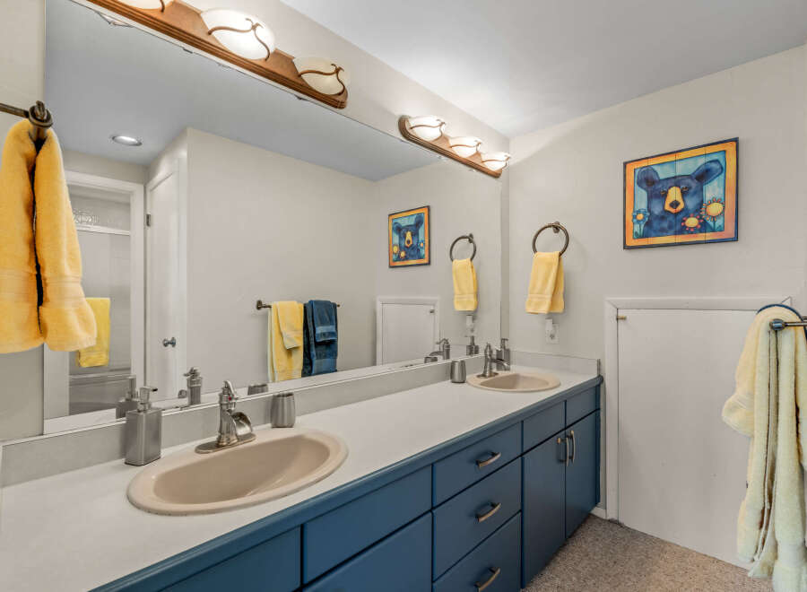 This charming bathroom features a double vanity with a sleek blue cabinet, offering ample storage space.
