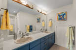 This charming bathroom features a double vanity with a sleek blue cabinet, offering ample storage space.