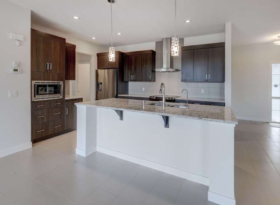 This modern kitchen boasts sleek dark wood cabinetry, stainless steel appliances, and a spacious island with a granite countertop.