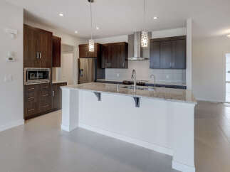 This modern kitchen boasts sleek dark wood cabinetry, stainless steel appliances, and a spacious island with a granite countertop.