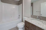 This modern bathroom features a sleek white bathtub and a stylish vanity with a granite countertop.