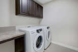 This laundry room features a modern design with sleek white appliances and dark wood cabinetry.