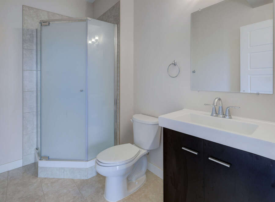 Step into this modern bathroom featuring a sleek glass shower enclosure and a stylish vanity with ample storage.