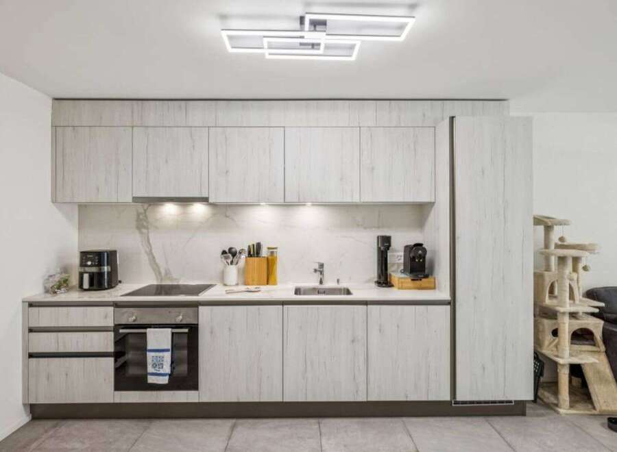 This modern kitchen boasts sleek, light-colored cabinetry and a stylish marble backsplash.