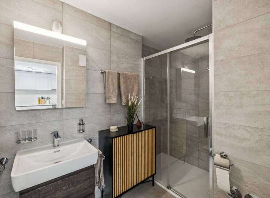 Step into this modern bathroom, featuring sleek gray tile and a spacious glass shower.