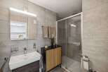 Step into this modern bathroom, featuring sleek gray tile and a spacious glass shower.