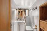 Step into this charming bathroom, featuring a unique design with mosaic tile walls and a wooden vanity.