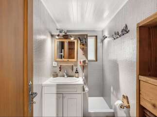 Step into this charming bathroom, featuring a unique design with mosaic tile walls and a wooden vanity.