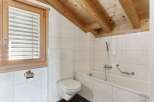 This charming bathroom features a bright and airy design with white tiled walls and a wooden beamed ceiling.
