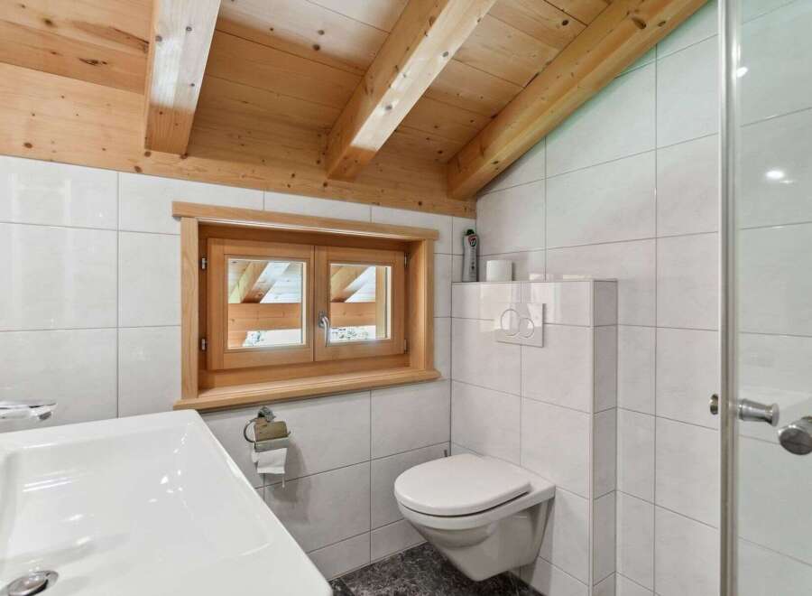 This charming bathroom features a unique wooden ceiling and a small window that allows natural light to flood the space.