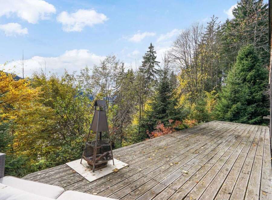 Enjoy breathtaking views from this stunning property featuring a spacious wooden deck, perfect for outdoor gatherings.
