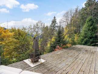 Enjoy breathtaking views from this stunning property featuring a spacious wooden deck, perfect for outdoor gatherings.