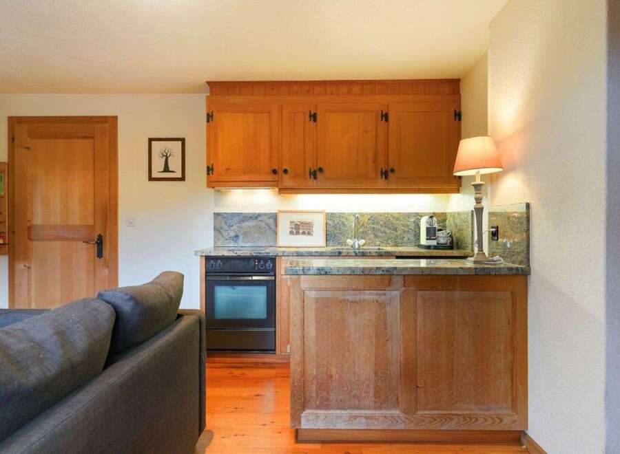 This charming kitchen features warm wooden cabinetry and a granite countertop, creating a cozy and inviting atmosphere.