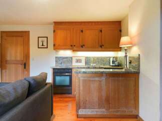 This charming kitchen features warm wooden cabinetry and a granite countertop, creating a cozy and inviting atmosphere.