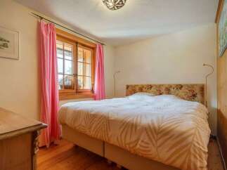 This charming bedroom features a cozy atmosphere with its wooden floors and a comfortable bed.
