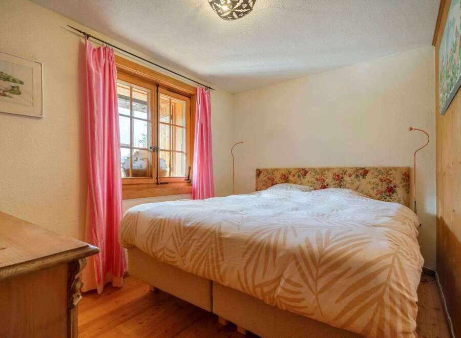 This charming bedroom features a cozy atmosphere with its wooden floors and a comfortable bed.