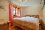 This charming bedroom features a cozy atmosphere with its wooden floors and a comfortable bed.