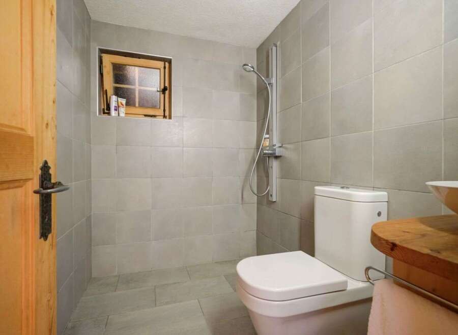 This charming bathroom features a cozy, rustic design with a wooden door and window frame.