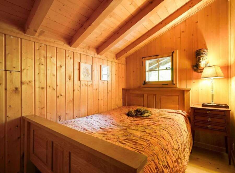 This cozy bedroom features warm wooden paneling and a charming, rustic aesthetic.