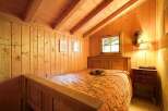 This cozy bedroom features warm wooden paneling and a charming, rustic aesthetic.