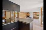 Discover the epitome of modern living in this stunning property, featuring a sleek kitchen with dark cabinetry and a contemporary countertop.