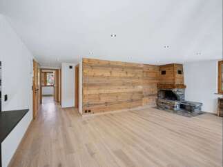 This stunning property boasts a warm and inviting interior, featuring a beautiful wooden accent wall and a cozy fireplace.