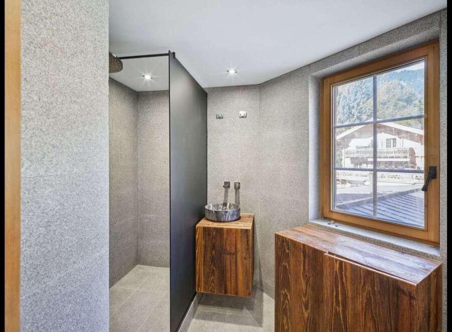 This modern bathroom features a sleek shower area with a dark partition, complemented by a stylish wooden vanity.