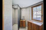 This modern bathroom features a sleek shower area with a dark partition, complemented by a stylish wooden vanity.