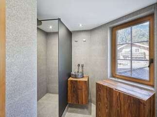 This modern bathroom features a sleek shower area with a dark partition, complemented by a stylish wooden vanity.