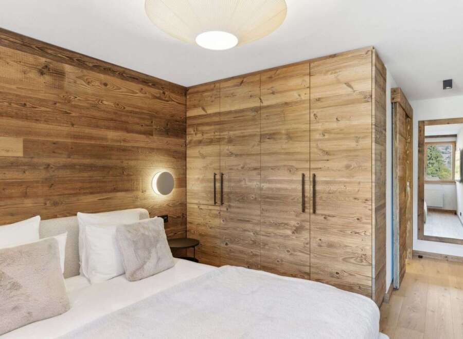 Experience rustic elegance in this stunning bedroom featuring exquisite wood paneling and a modern design.
