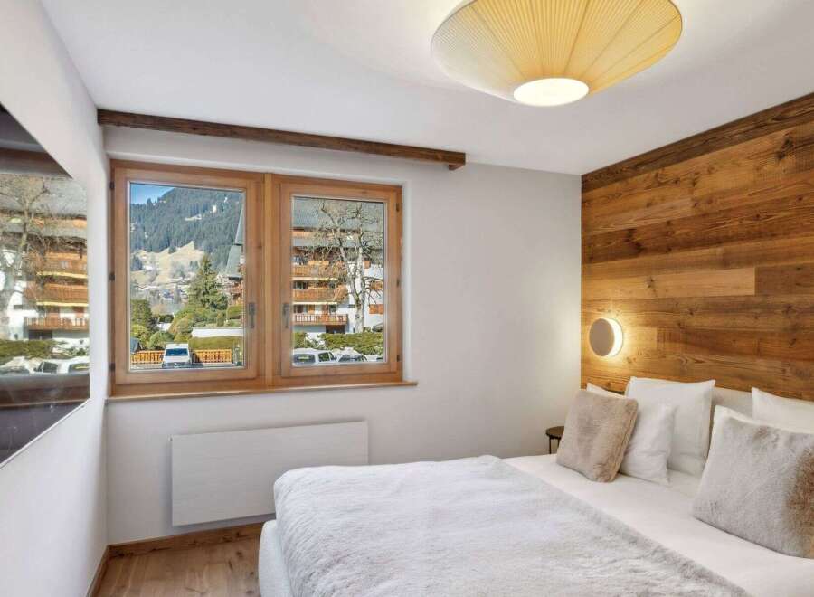 Experience the charm of this cozy bedroom, featuring a stunning wooden accent wall and a bright, airy ambiance.