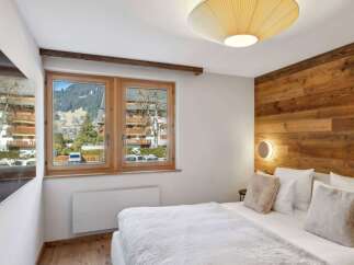 Experience the charm of this cozy bedroom, featuring a stunning wooden accent wall and a bright, airy ambiance.