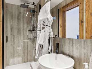 Step into luxury with this stunning bathroom featuring a sleek glass shower and a modern sink.