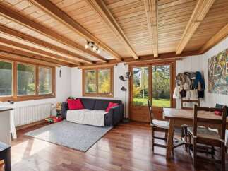 This charming property boasts a warm and inviting living space, featuring a beautiful wooden ceiling and hardwood floors.