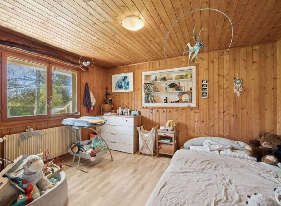 This charming bedroom features warm wooden paneling and a cozy atmosphere, perfect for a child's space.