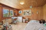 This charming bedroom features warm wooden paneling and a cozy atmosphere, perfect for a child's space.