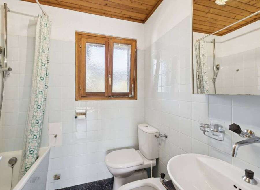 This charming bathroom features a classic design with a wooden ceiling and a window that brings in natural light.
