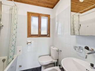 This charming bathroom features a classic design with a wooden ceiling and a window that brings in natural light.
