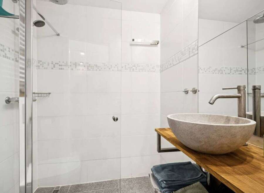 Step into a modern bathroom oasis! This stunning space features a sleek, frameless shower enclosure and elegant stone sink.